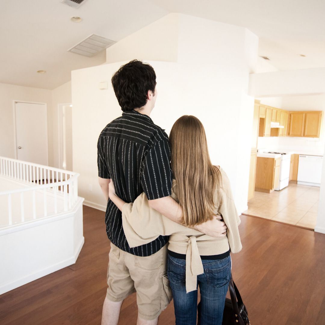 A couple with arms around each other looking at empty home